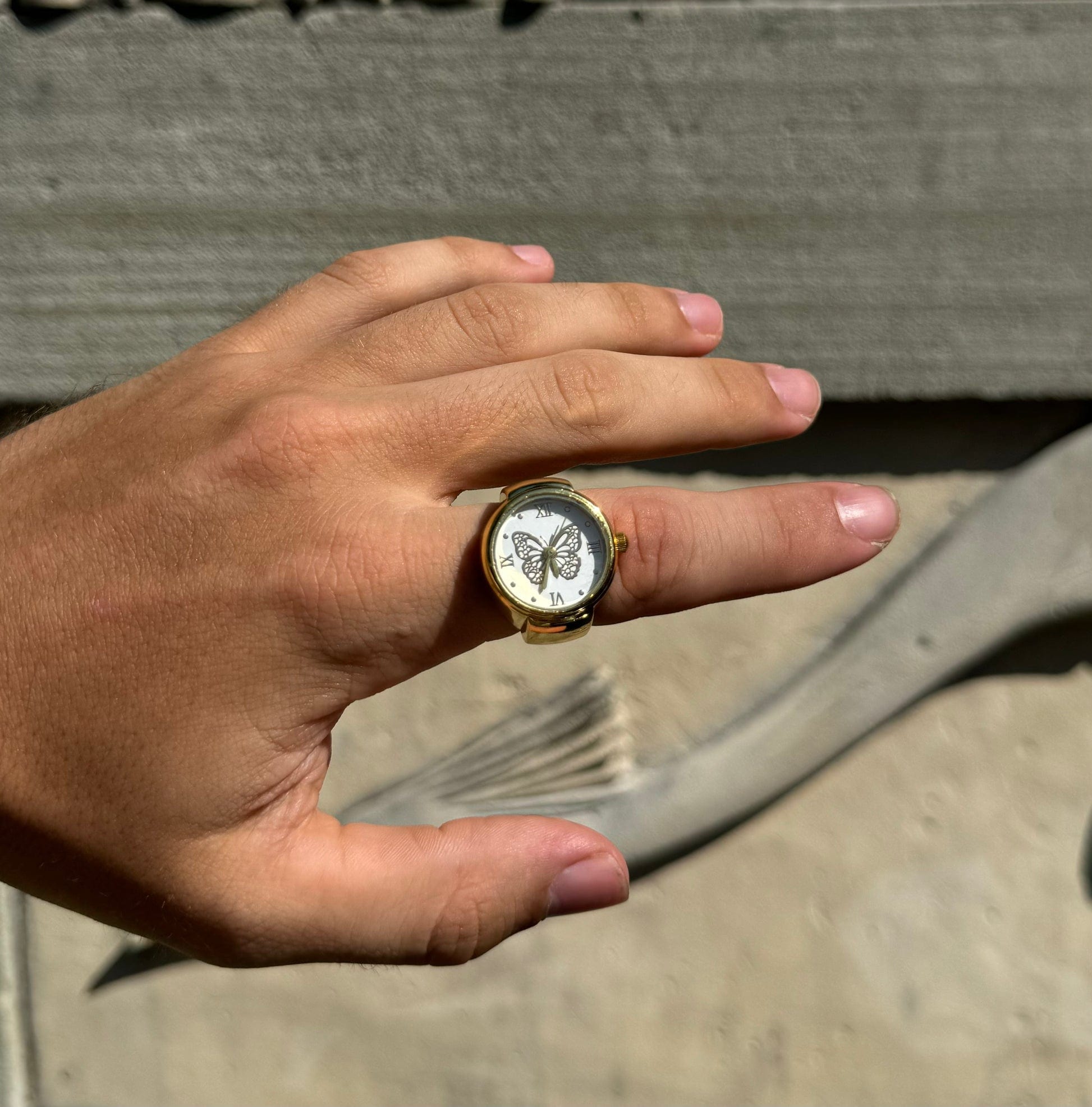Aperçu de la bague montre MBM dorée au cadran papillon sur un index masculin 