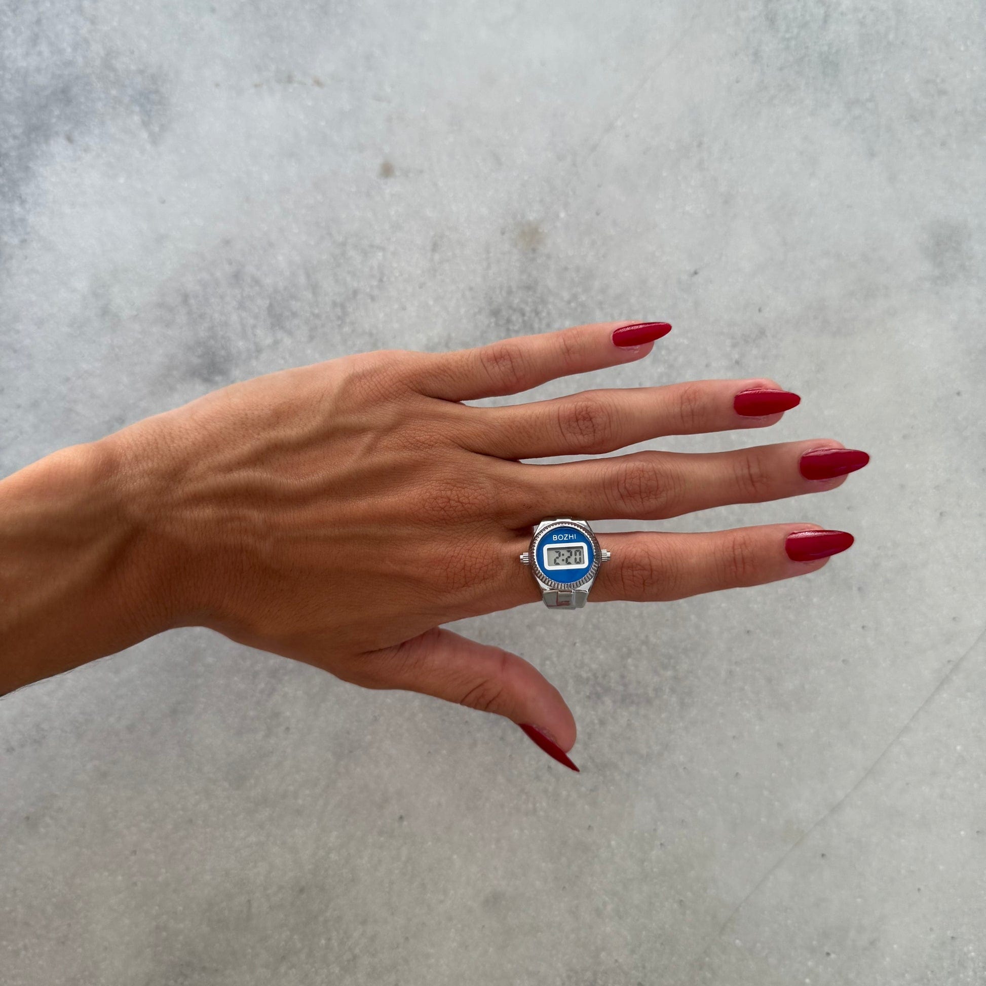 Bague Montre Argent - Cadran Digital Bleu portée sur un index féminin