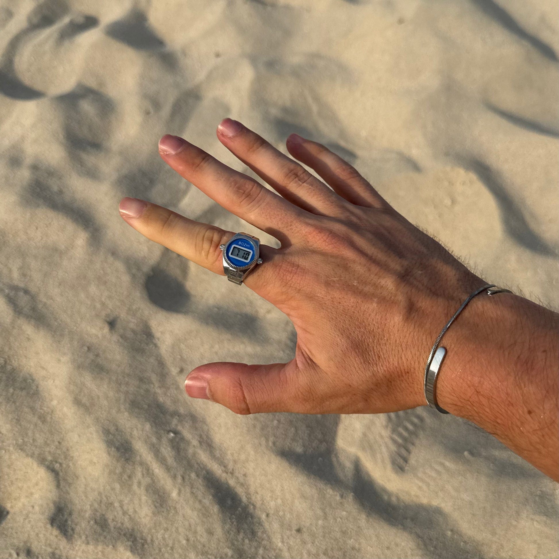 Bague Montre Argent - Cadran Digital Bleu portée sur un index masculin