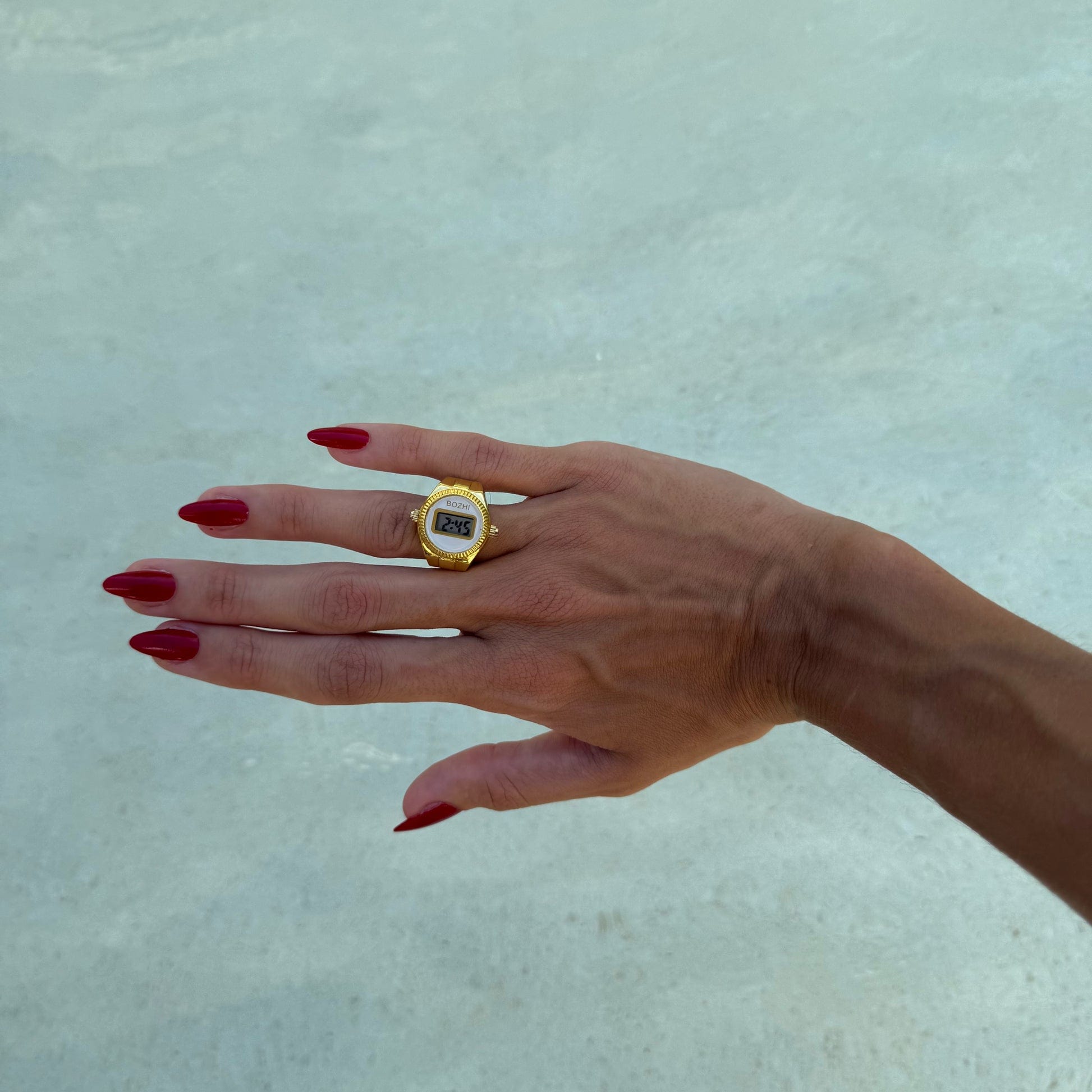 Bague Montre Dorée - Cadran Digital Blanc portée sur un annulaire féminin